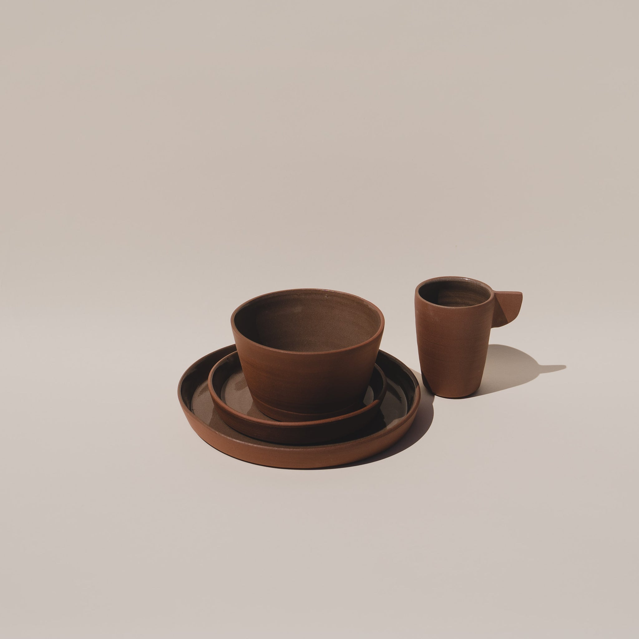 Ceramic plate set with ceramic bowl and ceramic mug in brown terracotta