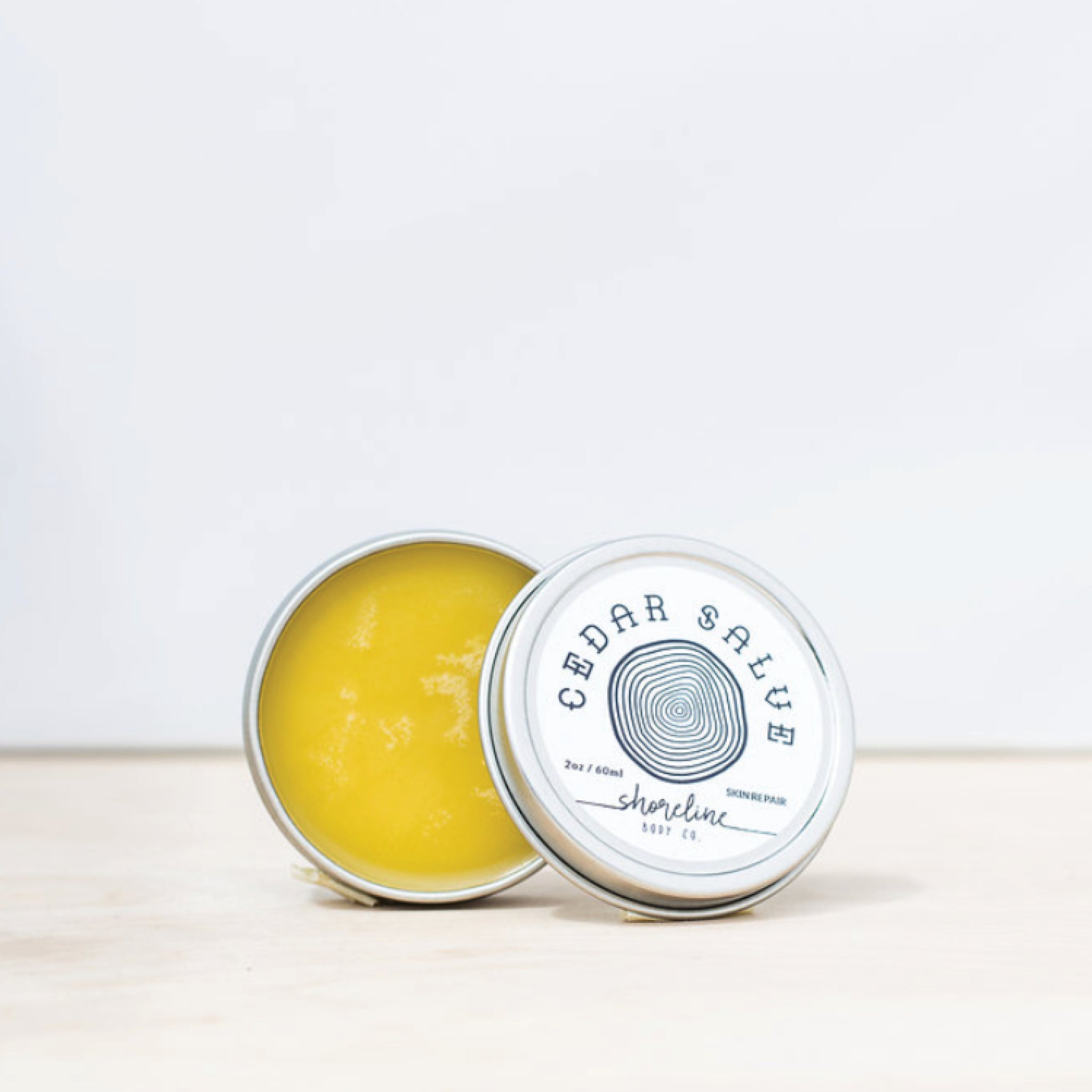 The Cedar Salve is pictured next to its lid against a white background. 