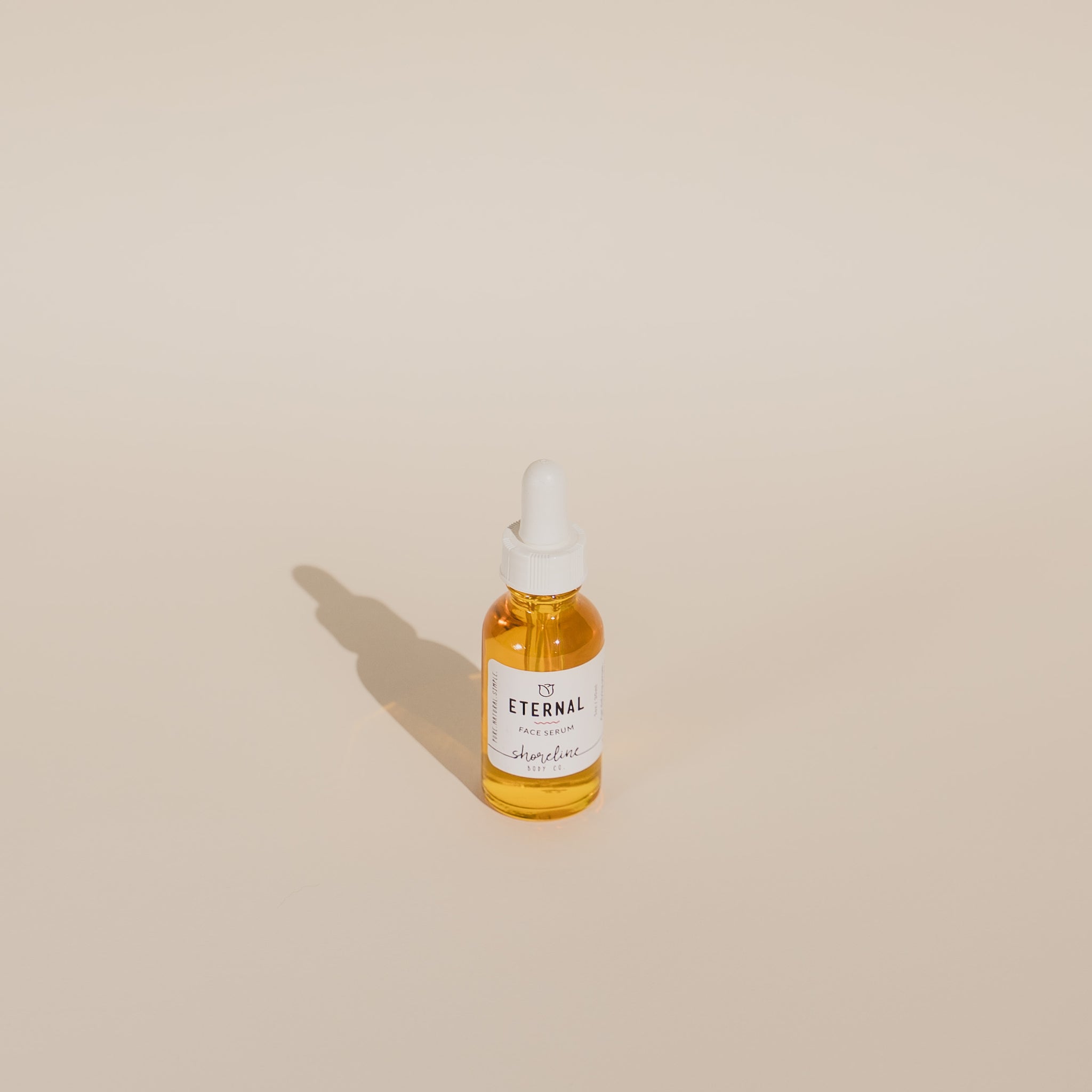 Eternal Serum is photographed against an off white background, illuminated by the sun. 