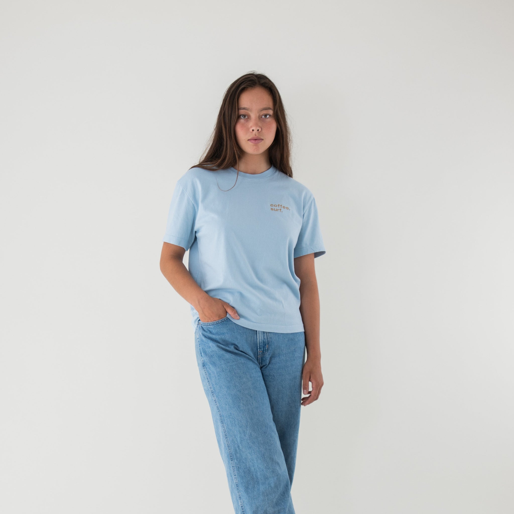 Organic cotton t-shirt in a creamy blue with "coffee. surf." embroidery over the left chest.